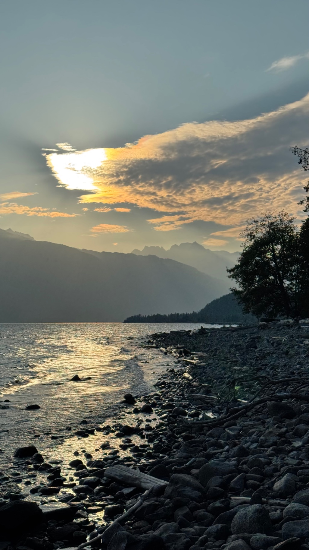 Rocky shoreline at sunset with mountains across the lake