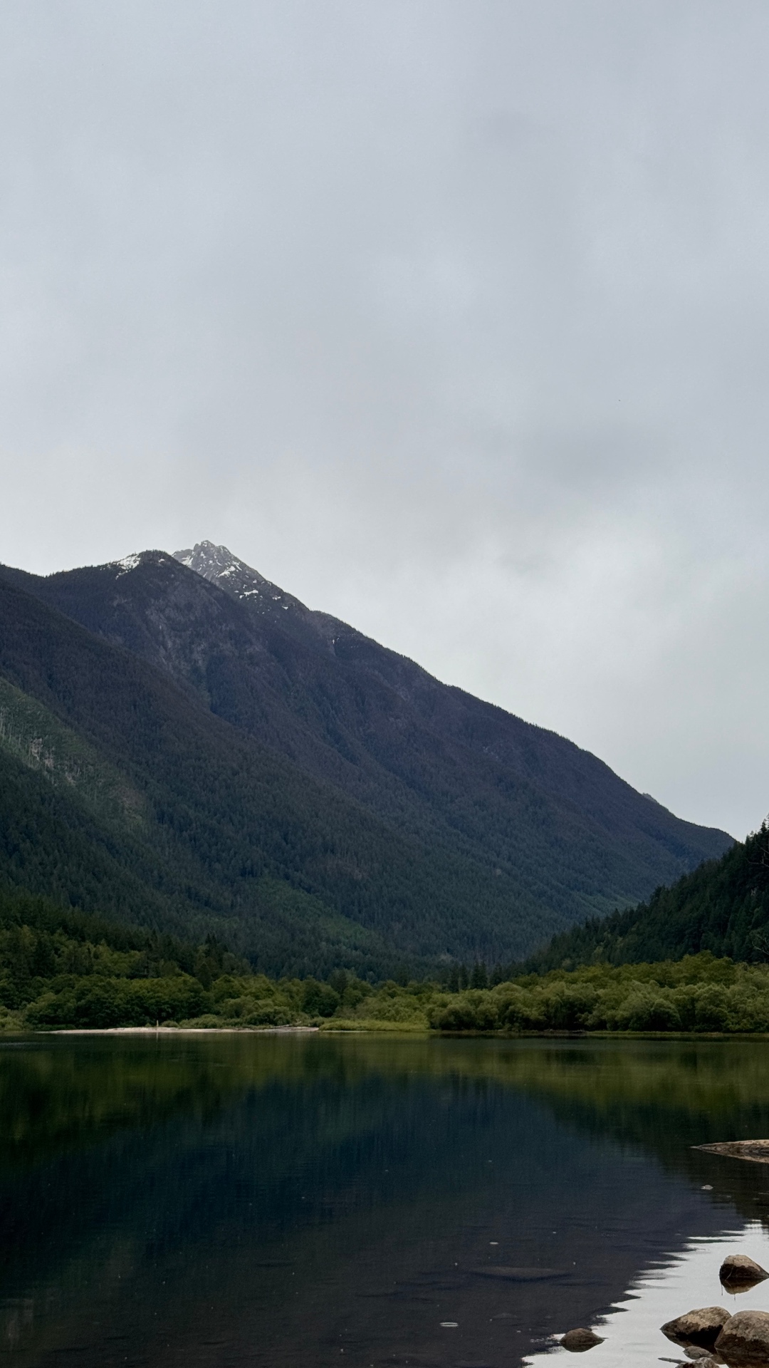 Snow-dusted peak rising above Silver Lake under a moody overcast sky