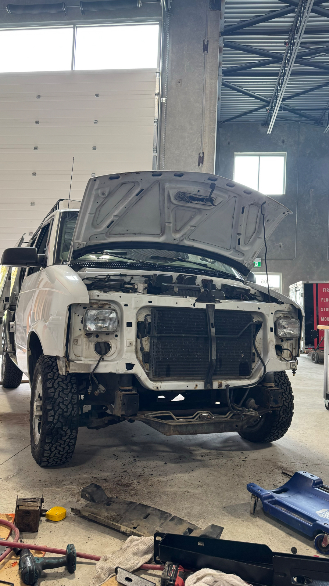Front end stripped down on the lift, showing the body lift gap above the frame rails