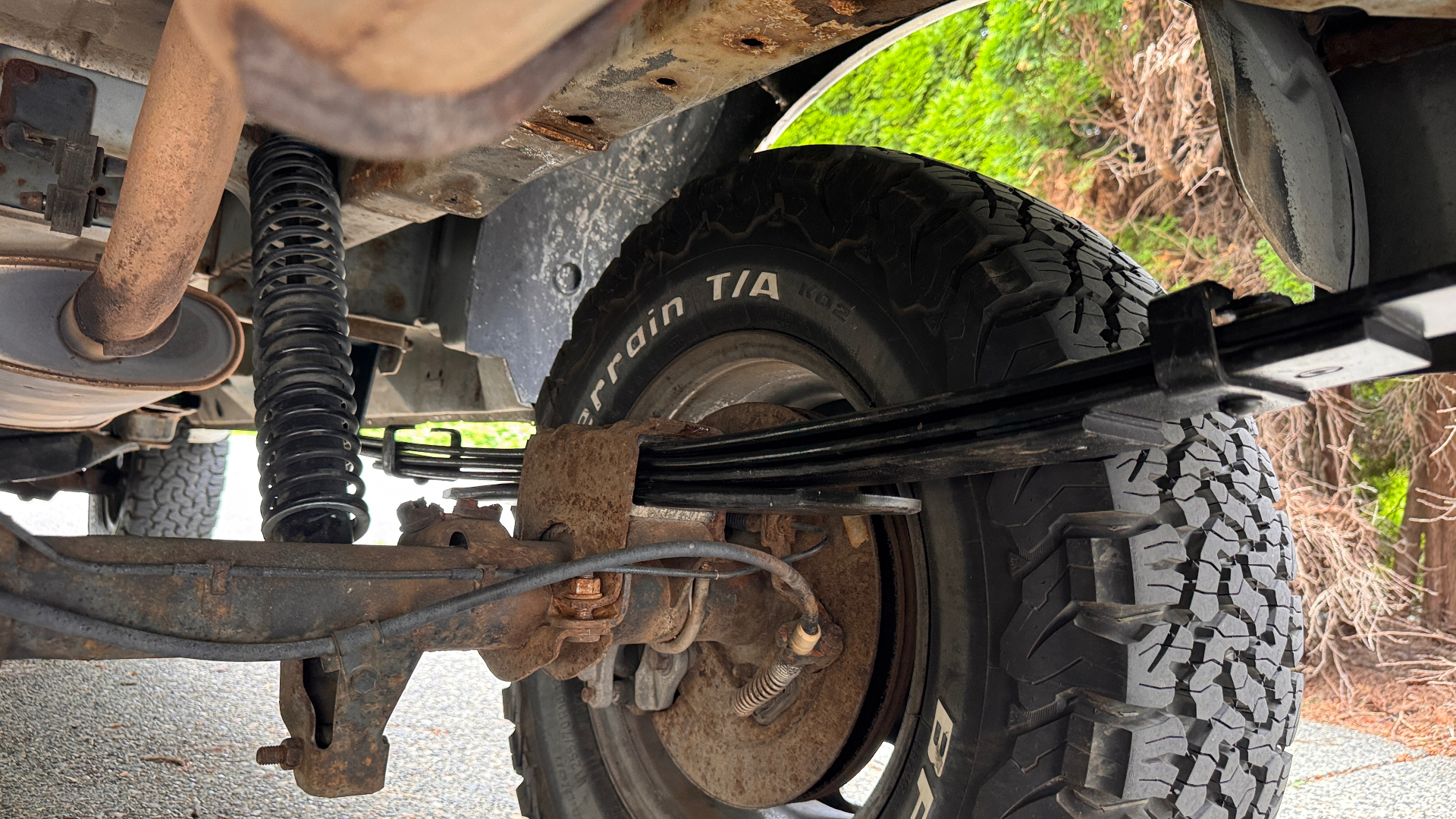 Under-van view of the new rear leaf pack, coil-over shock, and BFGoodrich KO2 tire on the lifted Astro at A&C Powersports.
