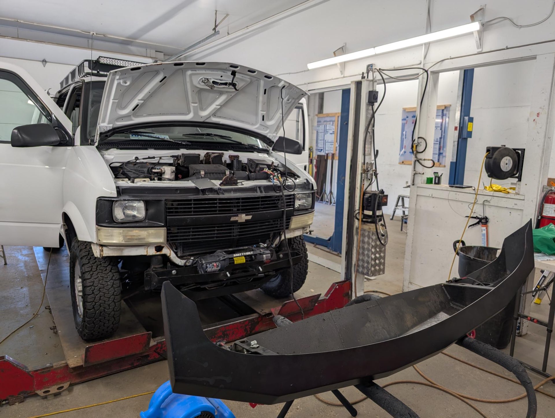 Astro on the hoist at Trademasters with the JOR bumper off, Smittybilt winch already mounted to the inner frame
