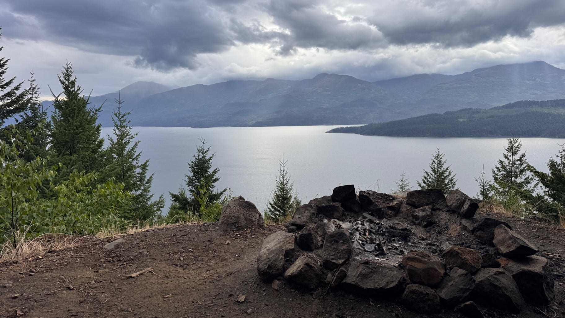 Close-up of the stone fire ring with mountains and lake beyond
